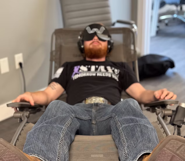Person reclining in the Shiftwave chair, eyes closed, calm lighting