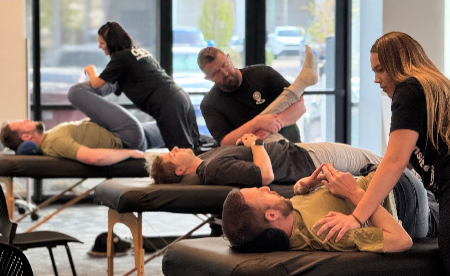Three OnSite practitioners guiding clients through stretches on adjacent tables